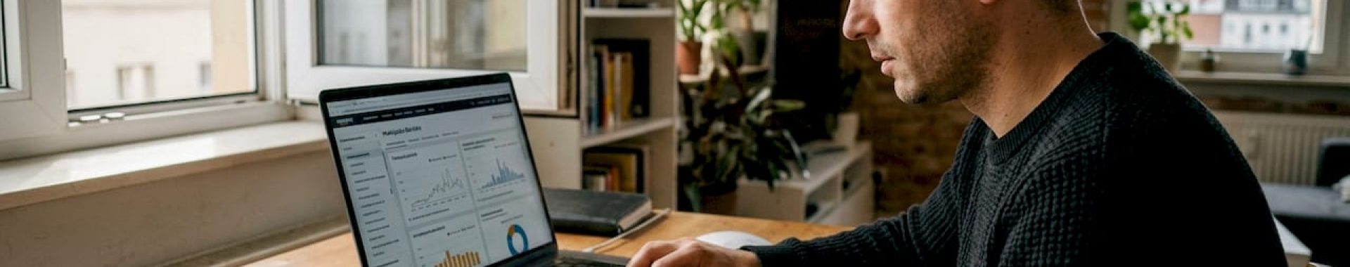 Ein Verkäufer sitzt an seinem überladenen Schreibtisch und wirft einen genauen Blick auf die aktuellen Amazon-Statistiken.