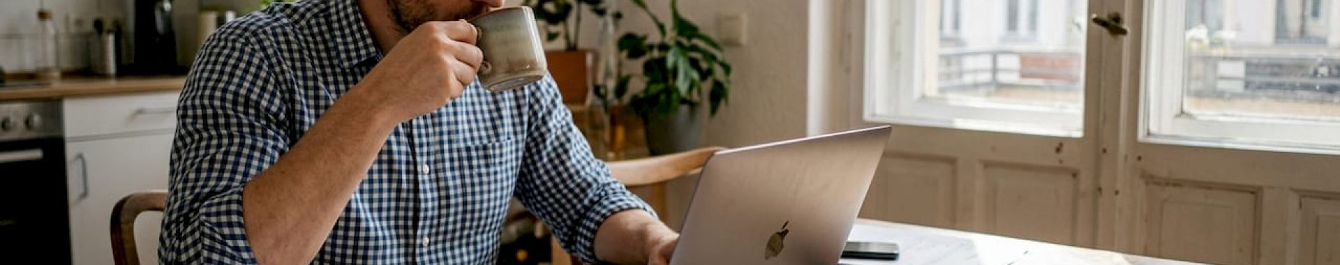 Ein Mann sitzt zu Hause am Schreibtisch und wirft einen genauen Blick auf die Werbekosten seiner Amazon-Kampagnen.