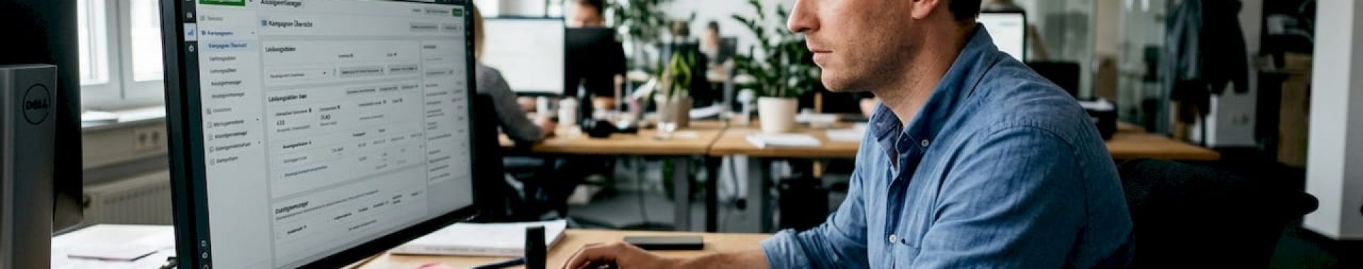 Ein Mann sitzt konzentriert an seinem Schreibtisch im Büro und arbeitet fokussiert an seinen Aufgaben.